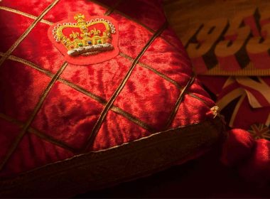 A plush red pillow with an elaborately embroidered crown.