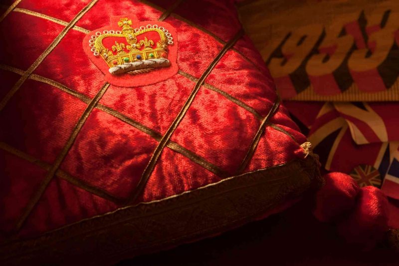 A plush red pillow with an elaborately embroidered crown.