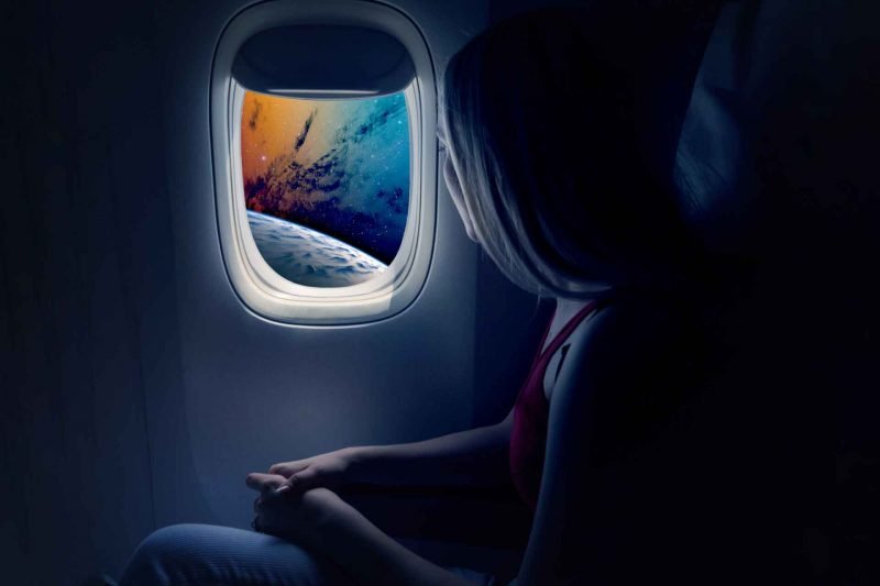 A futuristic travel photo of a woman flying high above a planet from a commercial space ship.