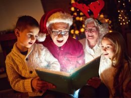 Grandparents and grandkids enjoying the magic of Christmas as they read a book together.