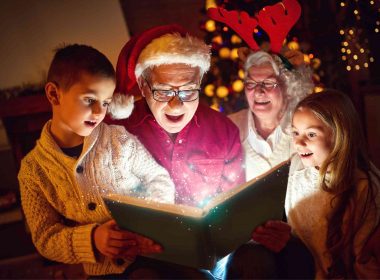 Grandparents and grandkids enjoying the magic of Christmas as they read a book together.