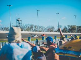 Fans cheering from the infield at the Daytona 500 on a sunny afternoon.