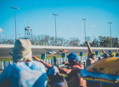 Fans cheering from the infield at the Daytona 500 on a sunny afternoon.