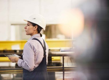 Assembly line worker on the manufacturing floor looking for someone.
