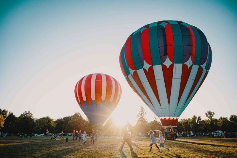 Two hot air balloons getting ready for a sunrise flight at a festival.