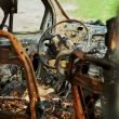 Close up of the cabin of a burned vehicle interior that has been gutted by a fire.