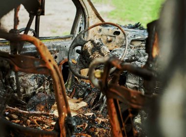 Close up of the cabin of a burned vehicle interior that has been gutted by a fire.