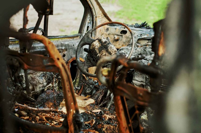 Close up of the cabin of a burned vehicle interior that has been gutted by a fire.