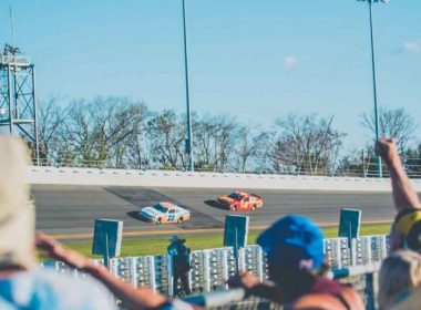 Fans cheering from the infield at the Daytona 500 on a sunny afternoon.
