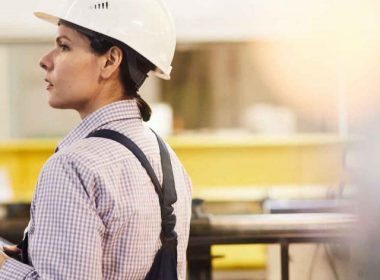Assembly line worker on the manufacturing floor looking for someone.