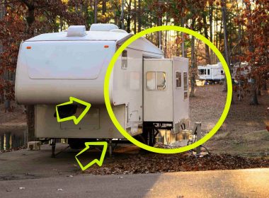 A fifth wheel with its slide extended in a campground.