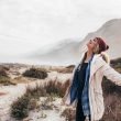 A woman happily breathes in fresh air down my the sea.