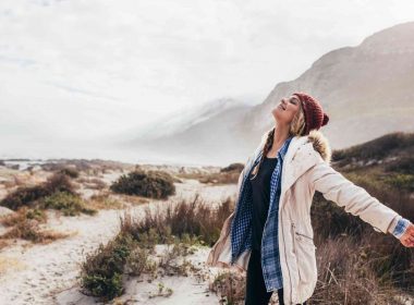 A woman happily breathes in fresh air down my the sea.