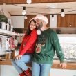 A couple adorned in Christmas sweaters and Santa hats having fun in their RV.