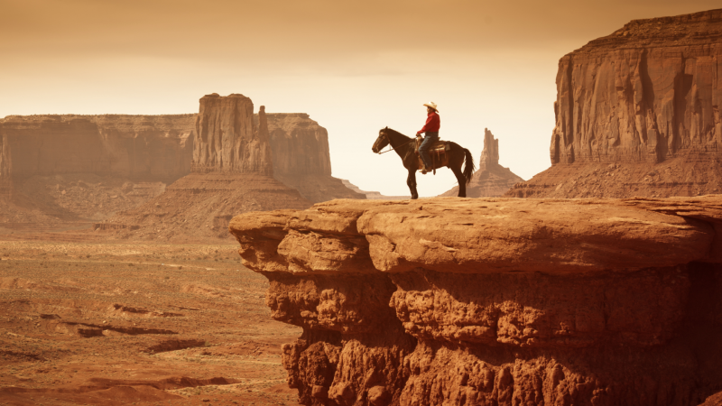 Cowboy on horse over rocky cliffs