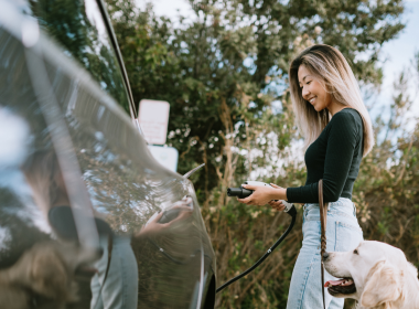 Woman charging electric vehicle on road trip