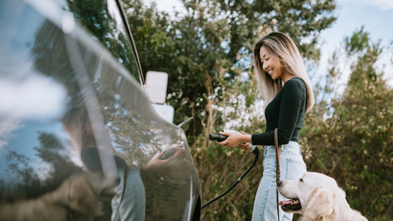 Woman charging electric vehicle on road trip