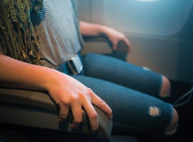 A person on an airplane using both armrests.