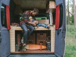 A man with his son sitting in camper van in forest