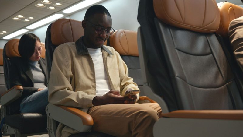 man using his phone not in airplane mode while flying
