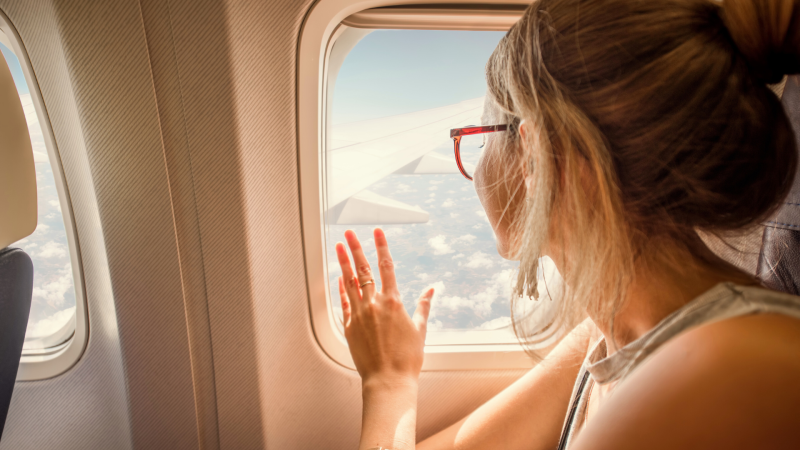 Woman looking out window on an airplane.