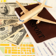 Toy airplane sitting atop a passport, plane ticket, and $130 in cash.
