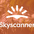 Skyscanner logo in front of orange background with palm fronds.