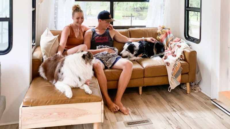 The couple from WIld RV life enjoying time on their couch with their dogs inside their RV.