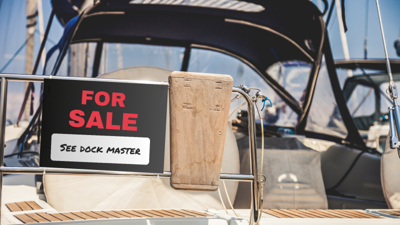 Boat tied to dock with a for sale sign on it.