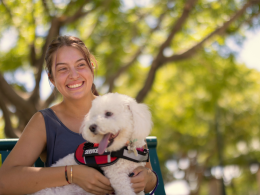 Woman holding service dog while sitting on a bench outside.
