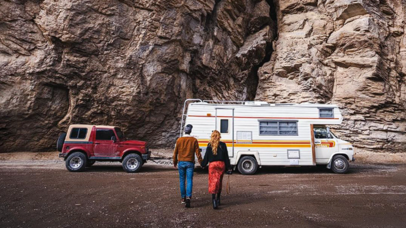 The Endless Adventure facing their Coachmen RV Motorhome with their Red Jeep being towed behind it.