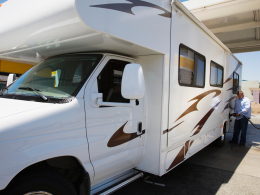A person filling up their motorhome with gas at a gas pump.