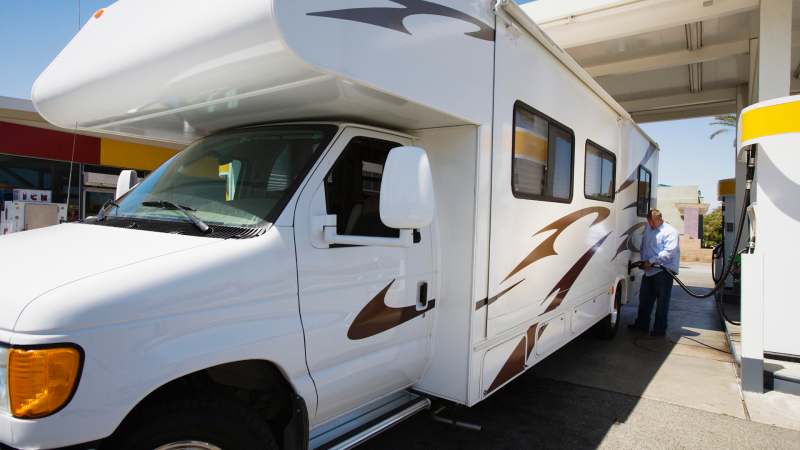 A person filling up their motorhome with gas at a gas pump.