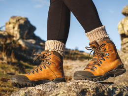 An upclose photo of a person's feet standing on a rock with hiking boots on and heavy socks.