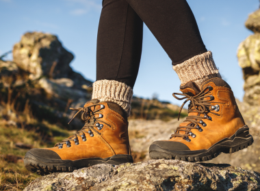 An upclose photo of a person's feet standing on a rock with hiking boots on and heavy socks.