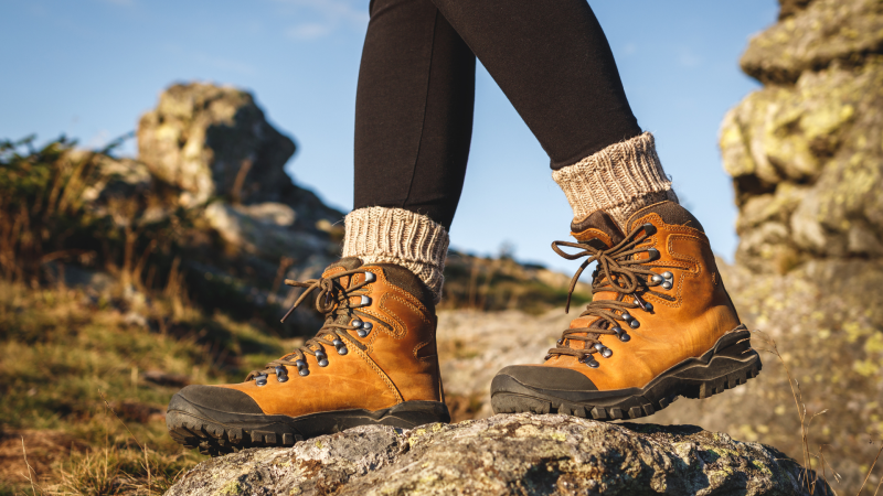 An upclose photo of a person's feet standing on a rock with hiking boots on and heavy socks.