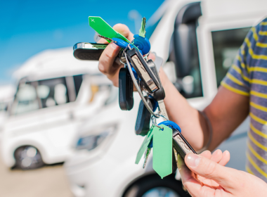 Person holding keys in front of a lot of RV's.