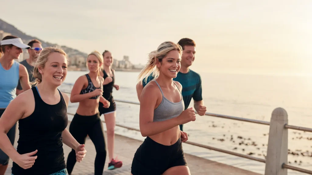 A group of seven people running on a pier at dusk. 