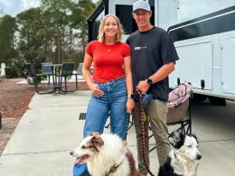 Wild RV Life and their two dogs as they pose for a photo beside their RV.