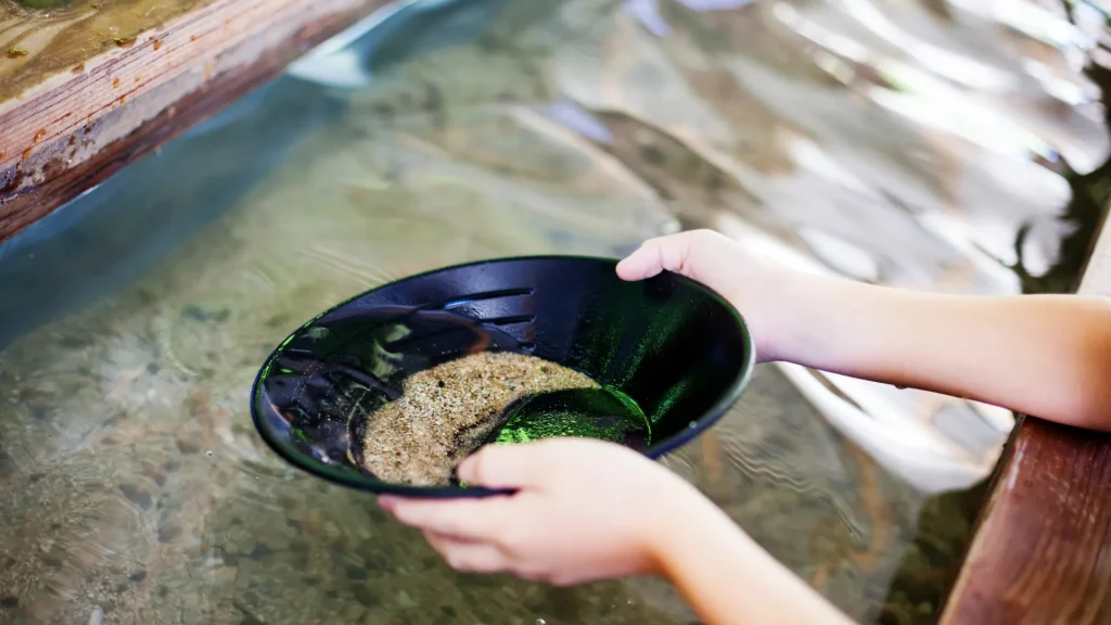 A person panning for gold in a contained setup for panning gold. 