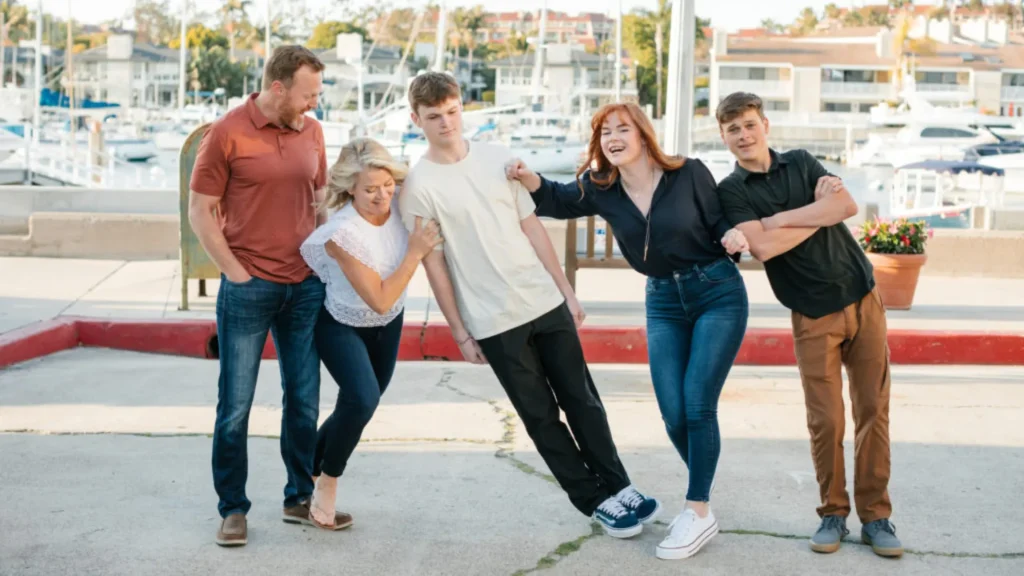 Keep Your Daydream's Tricia and Marc with their adolescent daughter and two sons taking a silly family portrait in front of a boat port.
