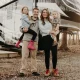 Nathan and Marissa from Less Junk, More Journey with their two children as they stand holding them on their hips in front of their RV.