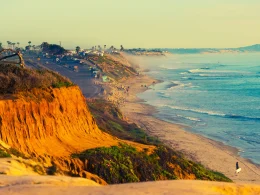 Encinitas Beach in southern California. This photo depicts a sepia toned photograph of bright blue waters and orange cliffs looking out to the ocean.