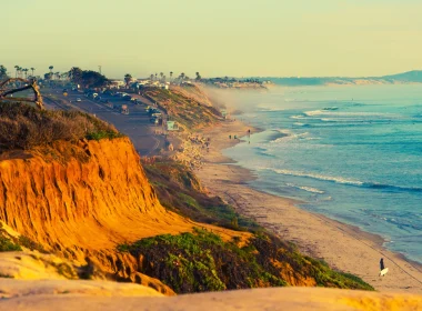Encinitas Beach in southern California. This photo depicts a sepia toned photograph of bright blue waters and orange cliffs looking out to the ocean.