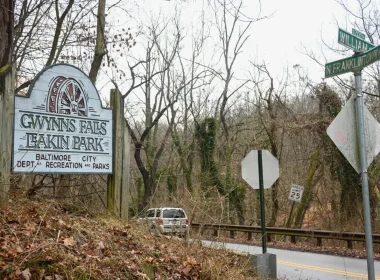 An image of the signage to Leakin Park and Gywnns Falls at the corner of a roadway.