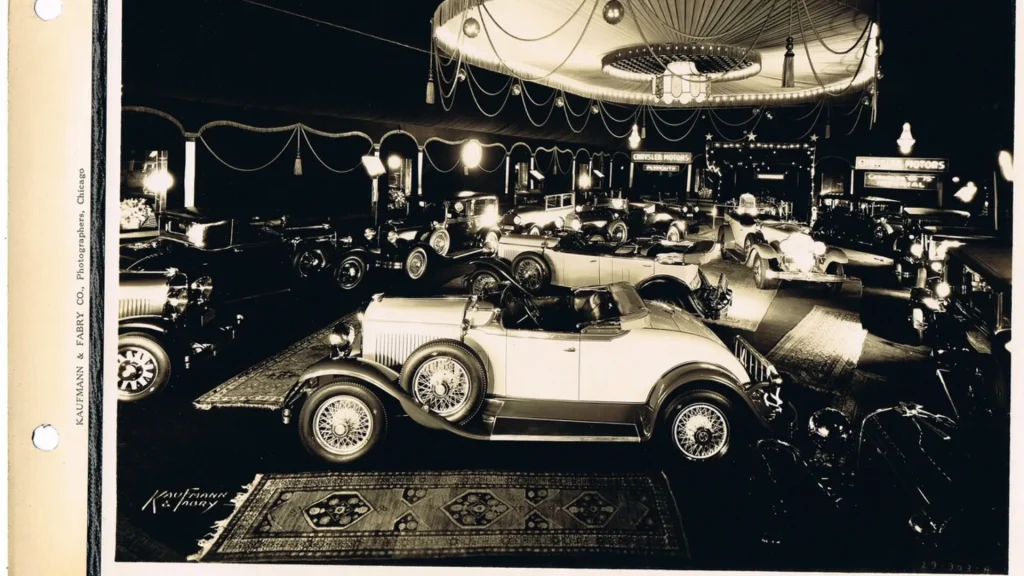A vintage photo from the Congress Plaza Hotel with vintage cars being showcased in the grand display. 
