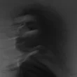 A black and grey blurry photo of a person in motion, giving it an eerie feeling.