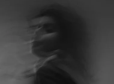 A black and grey blurry photo of a person in motion, giving it an eerie feeling.