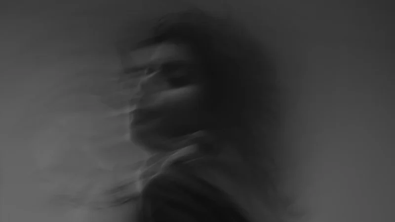 A black and grey blurry photo of a person in motion, giving it an eerie feeling.