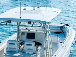 A recreational fishing boat on the ocean driving across the bright blue waters.